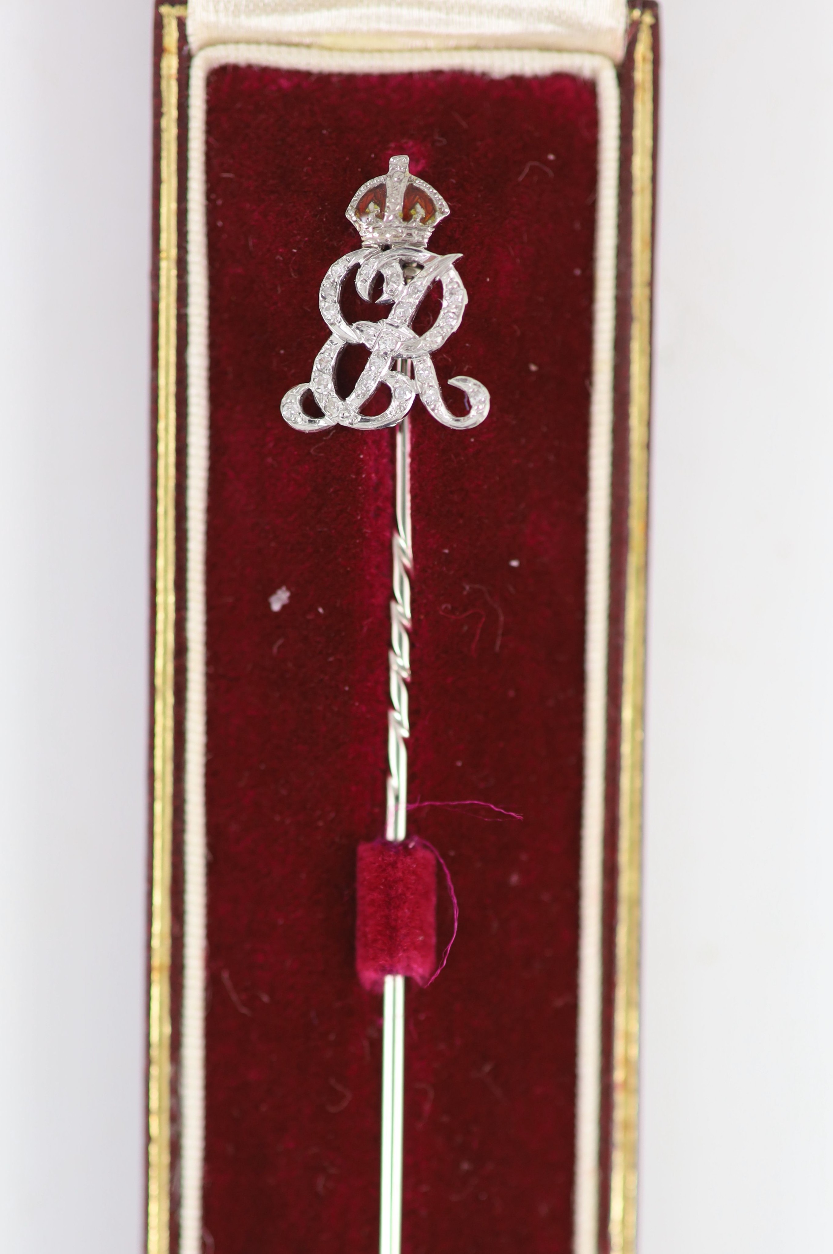 A white gold stick pin with diamond and red enamel monogram ‘’ER’’, beneath a crown, in Collingwood presentation box.
